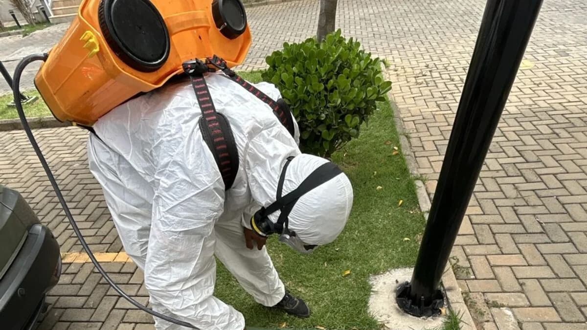Técnico com EPI completo em serviço de dedetização e controle de pragas em área externa